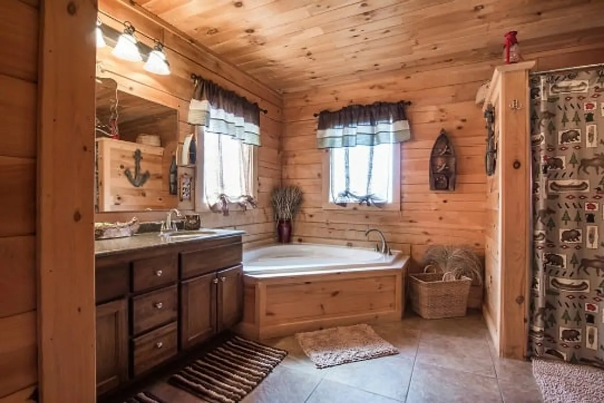 A spacious bathroom with a large bathtub, elegant vanity with a mirror, decorative accents, and calming colors. The space is bathed in natural light and designed for relaxation and self-care.