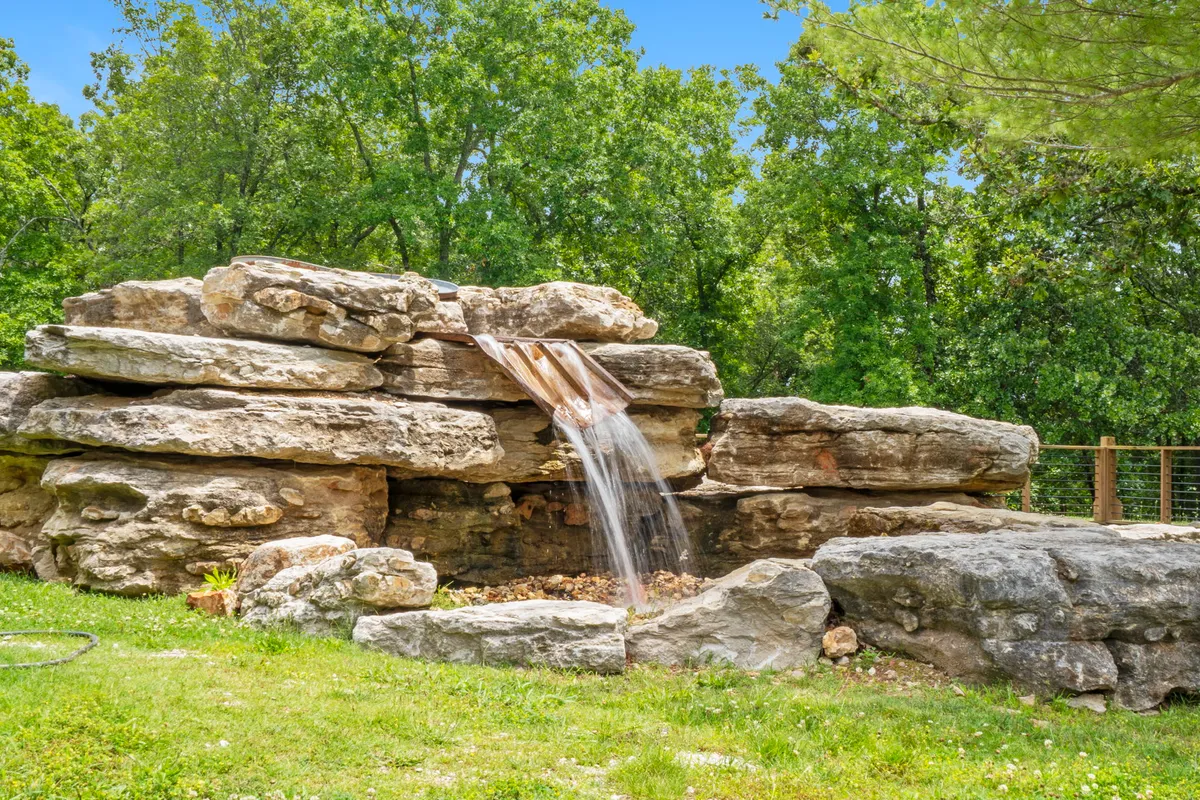 A tranquil natural waterfall cascades over rocks, surrounded by lush greenery. The scene exudes peace and highlights the beauty of Ozark nature, with plenty of wildlife habitat and spots for quiet reflection or adventure.