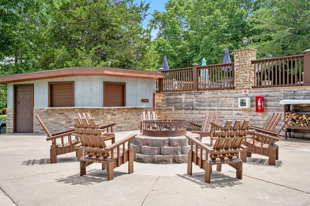 A cozy communal fire pit area is surrounded by wooden chairs and lush greenery. The setting invites families and friends to gather, socialize, and enjoy evenings under the stars.
